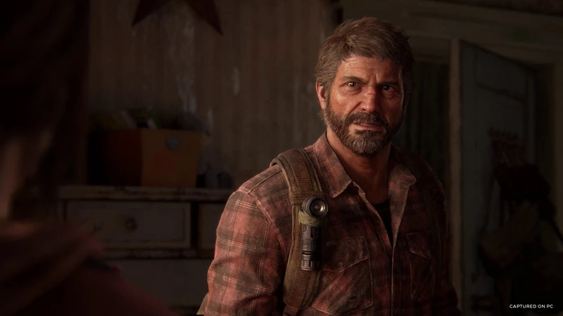 A close-up of Joel indoors in The Last of Us Part I
