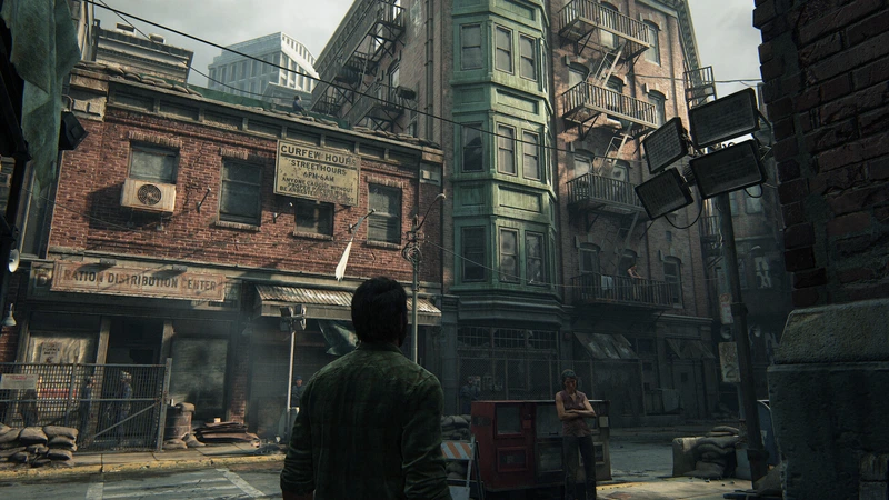 Joel looks up at buildings on a quarantine-zone street in The Last of Us Part I