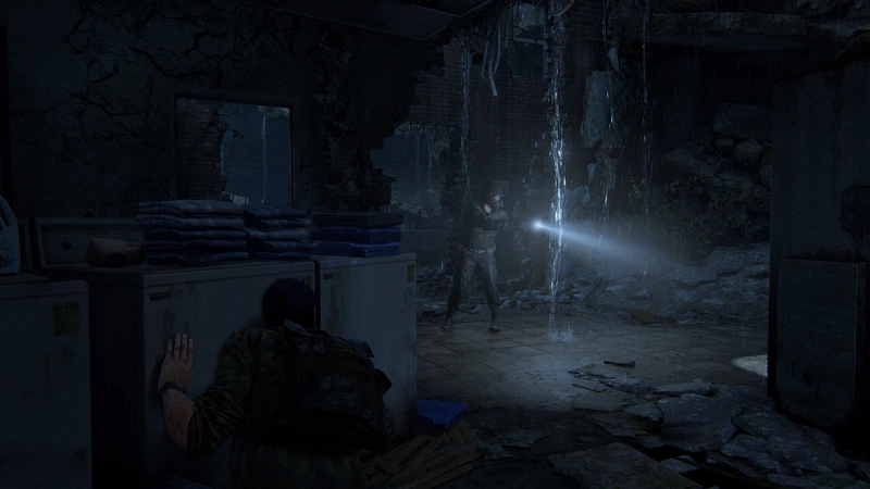 A flashlight illuminates a dark, damaged room in The Last of Us Part I