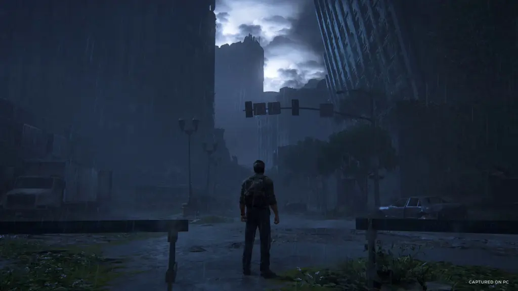 Joel stands on a rain-soaked city street in The Last of Us Part I
